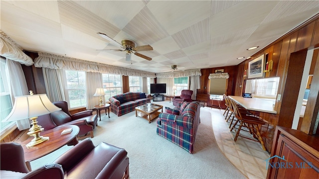 living room featuring wooden walls, light carpet, and ceiling fan