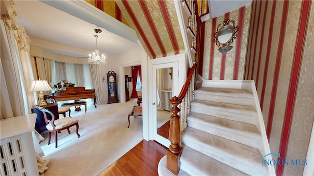 stairway featuring wood-type flooring, vaulted ceiling, and an inviting chandelier