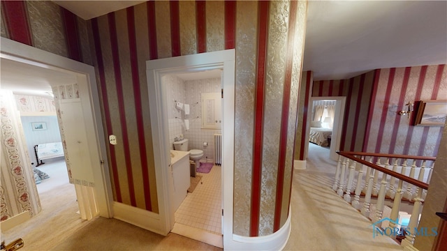 hallway featuring radiator and light colored carpet