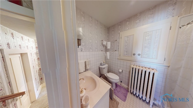 bathroom with tile walls, vanity, radiator heating unit, and toilet