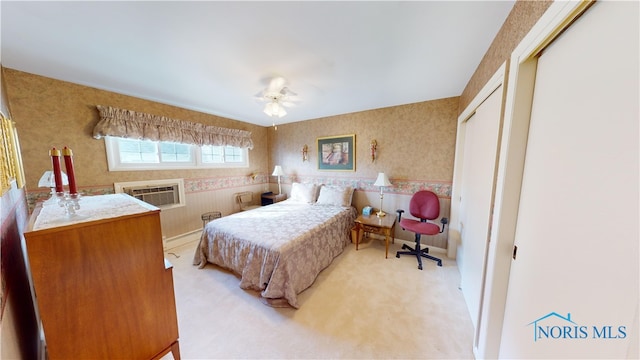 bedroom with an AC wall unit, a closet, light carpet, and ceiling fan