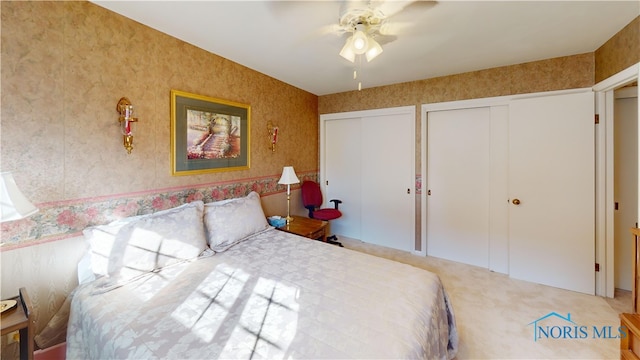 carpeted bedroom with ceiling fan and two closets