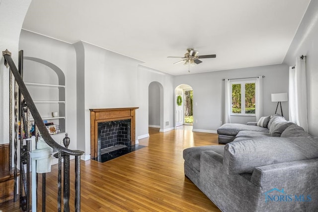 living room with ceiling fan, wood-type flooring, and built in shelves