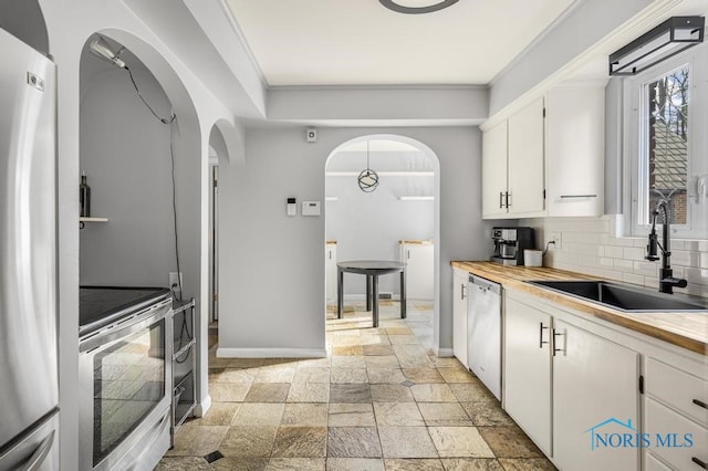 kitchen featuring stainless steel appliances, white cabinets, decorative backsplash, sink, and crown molding