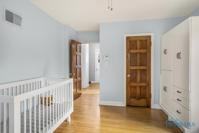 bedroom featuring a nursery area and light hardwood / wood-style floors