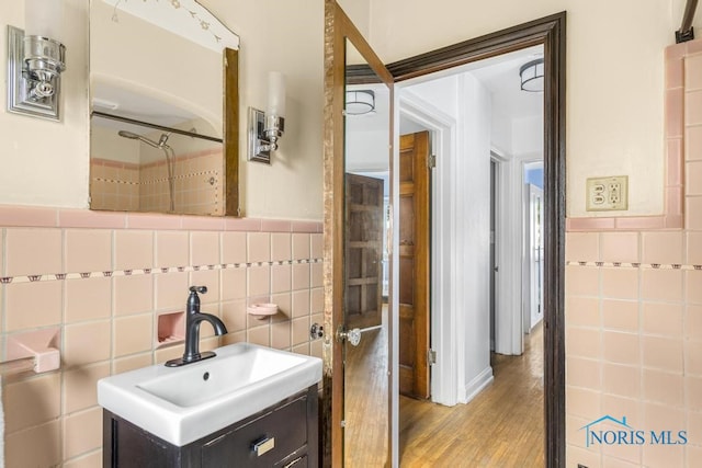 bathroom featuring tile walls, wood-type flooring, vanity, and a shower