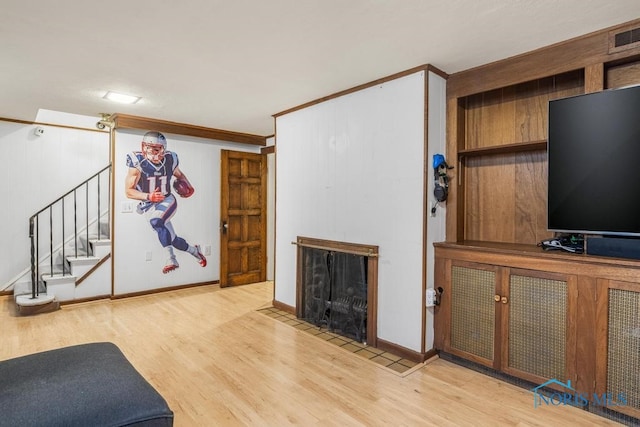 unfurnished living room with light wood-type flooring and ornamental molding