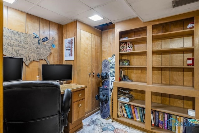 home office featuring a paneled ceiling, wood walls, and built in desk