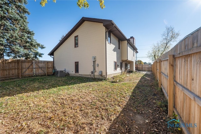 rear view of property featuring a yard and cooling unit