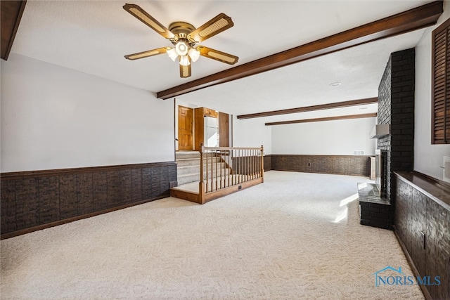 interior space featuring a fireplace, wooden walls, ceiling fan, and beam ceiling