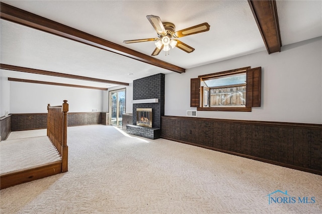 living room with beamed ceiling, wooden walls, light carpet, and a fireplace