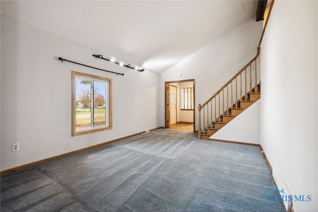 unfurnished living room with high vaulted ceiling and light carpet