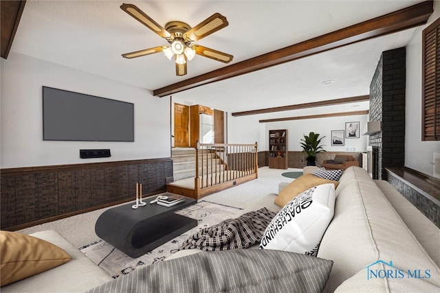 carpeted living room featuring beam ceiling, ceiling fan, and a brick fireplace