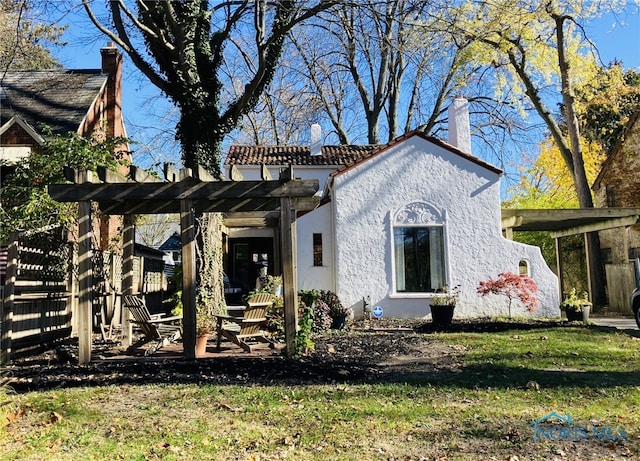 rear view of house with a yard and a pergola