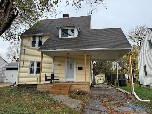 view of front of home with a front yard, a porch, and a shed