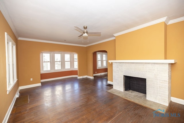 unfurnished living room with ceiling fan, crown molding, dark wood-type flooring, and a brick fireplace