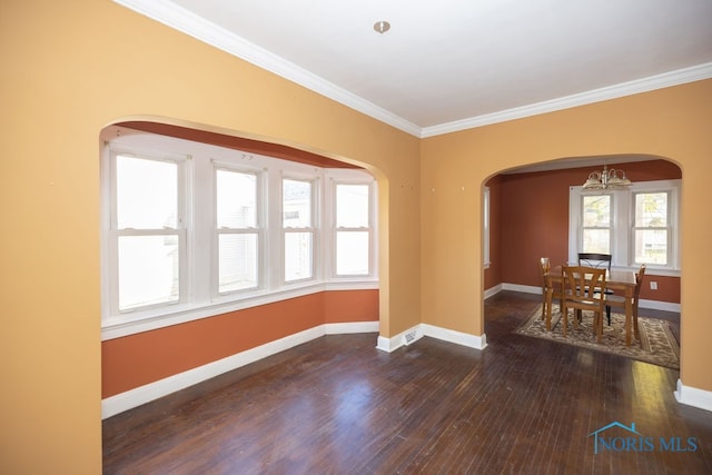 empty room with dark hardwood / wood-style floors, crown molding, and an inviting chandelier