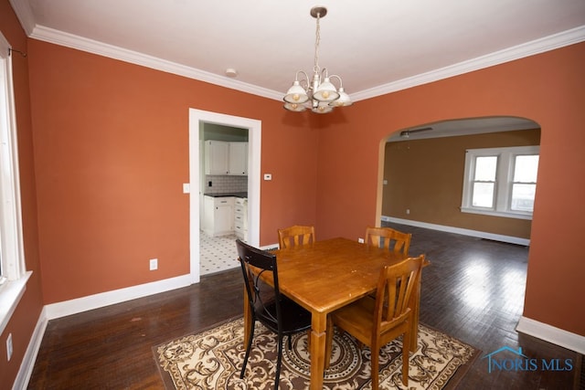 dining room featuring a chandelier, crown molding, and dark wood-type flooring