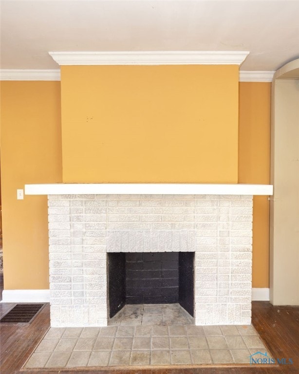 interior details with hardwood / wood-style floors, ornamental molding, and a brick fireplace