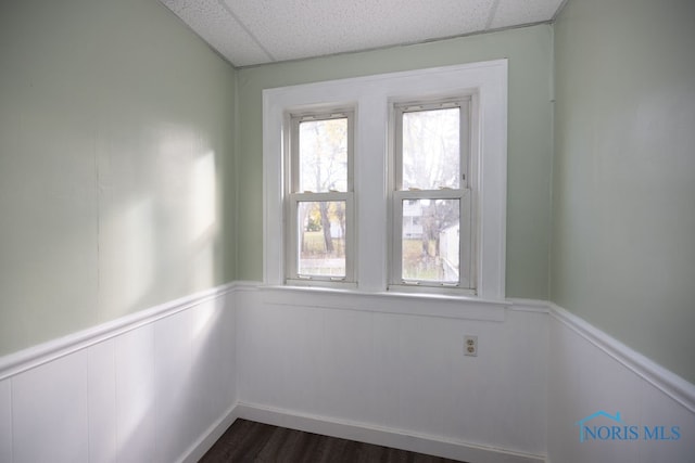 empty room featuring a paneled ceiling and dark hardwood / wood-style flooring