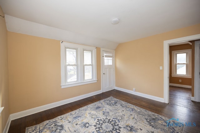 foyer with dark wood-type flooring, vaulted ceiling, and a healthy amount of sunlight