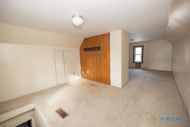 bonus room featuring light carpet, vaulted ceiling, and wooden walls