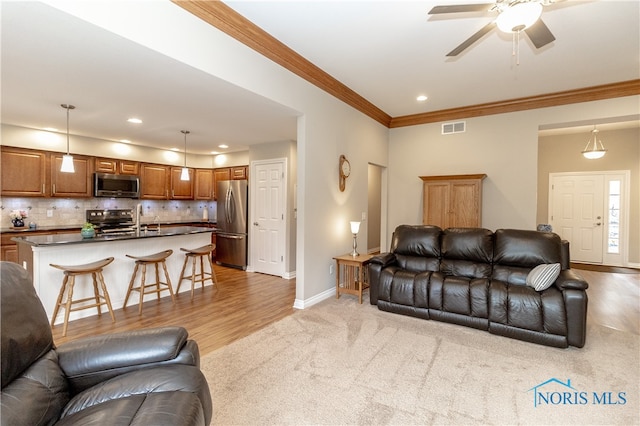 living room with ceiling fan, sink, light hardwood / wood-style flooring, and ornamental molding