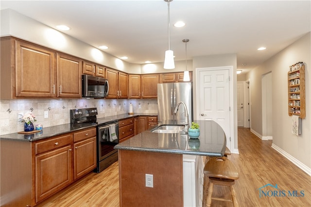 kitchen featuring light hardwood / wood-style floors, stainless steel appliances, sink, and an island with sink