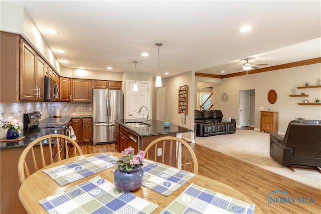 dining area featuring ceiling fan, sink, light hardwood / wood-style flooring, and ornamental molding