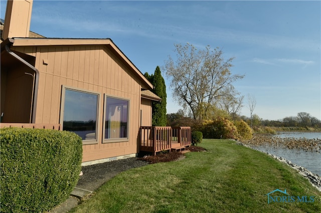 view of home's exterior featuring a deck with water view and a yard