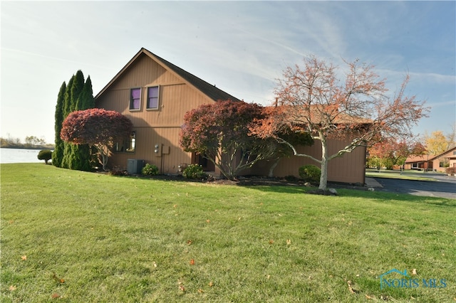 view of side of property featuring central air condition unit and a lawn