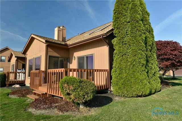 61 N Harbors End Dr, Port Clinton, OH 43452 - view of property exterior with a chimney, a wooden deck, a yard, and roof with shingles