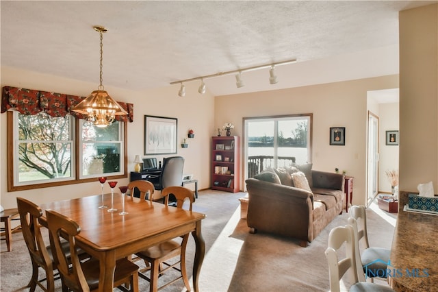 dining space featuring a chandelier, a textured ceiling, light carpet, and rail lighting