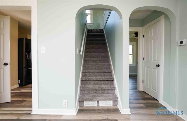 stairway with hardwood / wood-style floors and ceiling fan