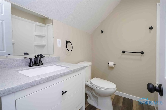 bathroom featuring wood-type flooring, toilet, vaulted ceiling, a textured ceiling, and vanity