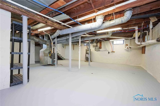 basement featuring electric water heater and heating unit