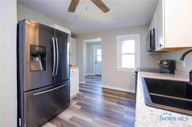 kitchen featuring appliances with stainless steel finishes, sink, light hardwood / wood-style floors, white cabinets, and ceiling fan