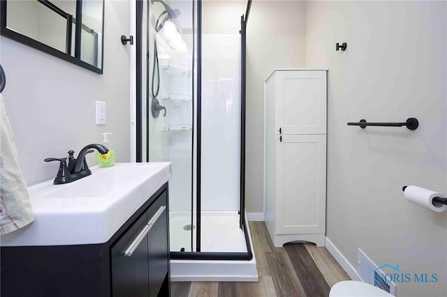 bathroom with vanity, hardwood / wood-style floors, and a shower with door