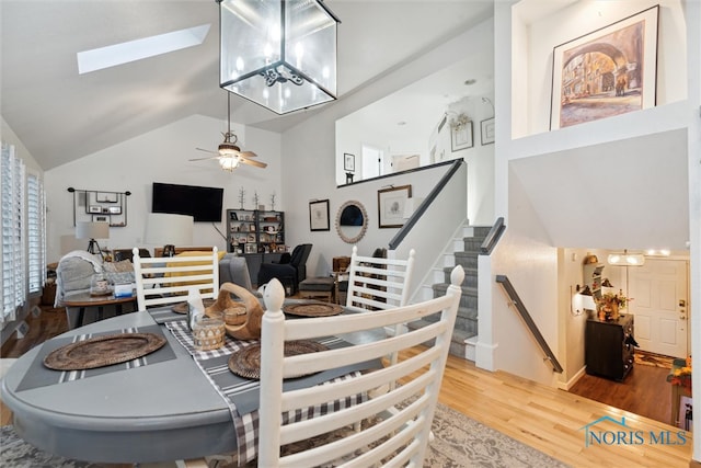 dining area with hardwood / wood-style floors, lofted ceiling with skylight, and ceiling fan