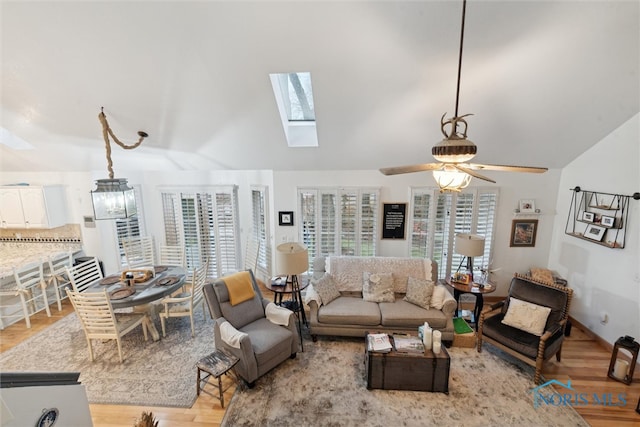 living room with ceiling fan, vaulted ceiling, and light wood-type flooring