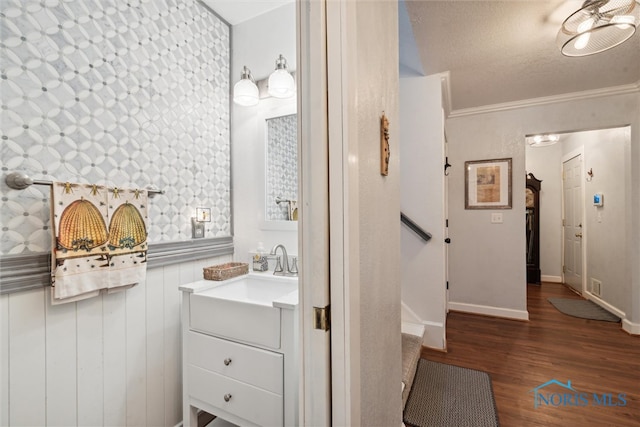 bathroom featuring hardwood / wood-style floors, vanity, ornamental molding, and a textured ceiling