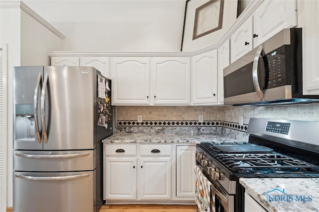 kitchen featuring stainless steel appliances, light stone counters, light hardwood / wood-style flooring, backsplash, and white cabinets