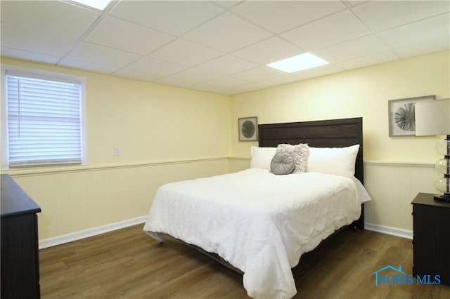 bedroom with a drop ceiling and dark hardwood / wood-style floors