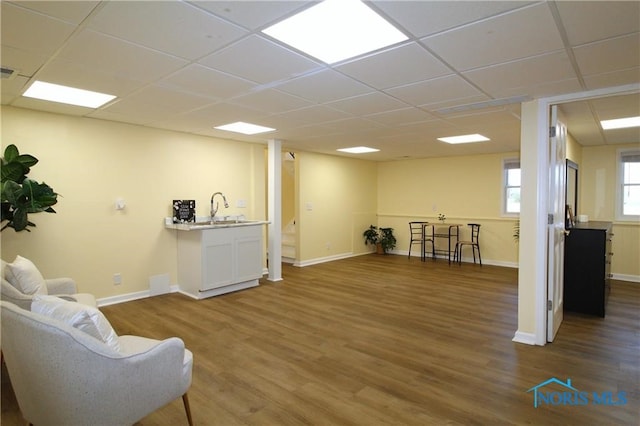 living area featuring sink, a drop ceiling, and wood-type flooring