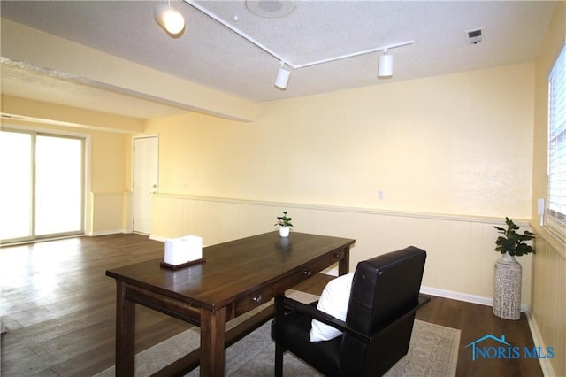 office space with dark hardwood / wood-style flooring, rail lighting, and a textured ceiling