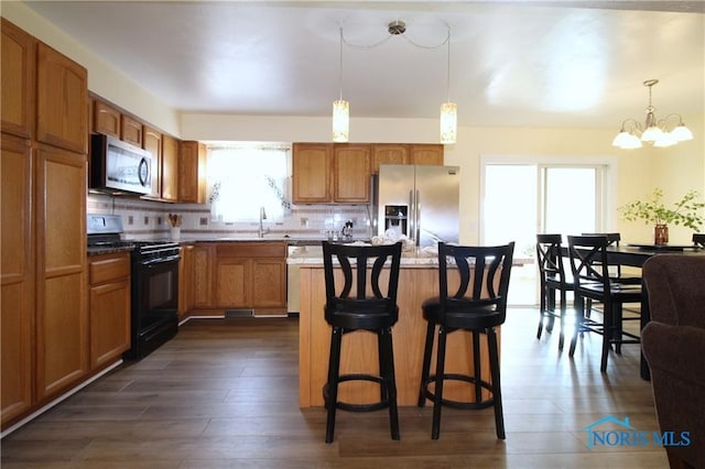 kitchen with decorative backsplash, stainless steel appliances, a center island, and decorative light fixtures