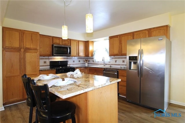 kitchen with dark hardwood / wood-style flooring, a kitchen island, tasteful backsplash, and stainless steel appliances