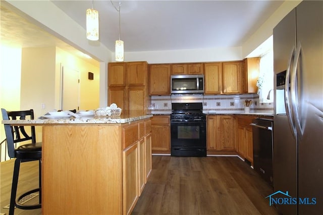 kitchen featuring a breakfast bar, black appliances, backsplash, a kitchen island, and dark wood-type flooring