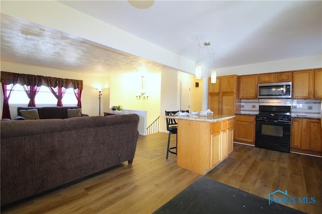 kitchen with dark hardwood / wood-style flooring, a kitchen island, black range with gas stovetop, and a kitchen breakfast bar