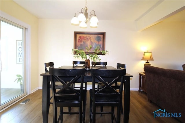 dining space with dark hardwood / wood-style flooring and a notable chandelier